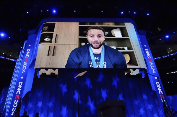 Displayed on a screen, Golden State Warriors guard Stephen Curry speaks during the Democratic National Convention in Chicago on Thursday, Aug. 22, 2024. (AP Photo/Brynn Anderson, File)